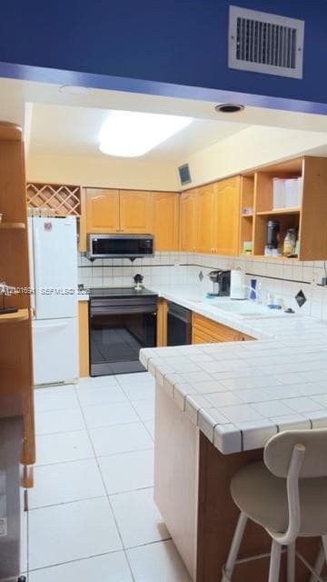 Kitchen featuring light-finish wood cabinetry, a built-in wine rack, tile countertops, integrated appliances, and ceramic tile flooring