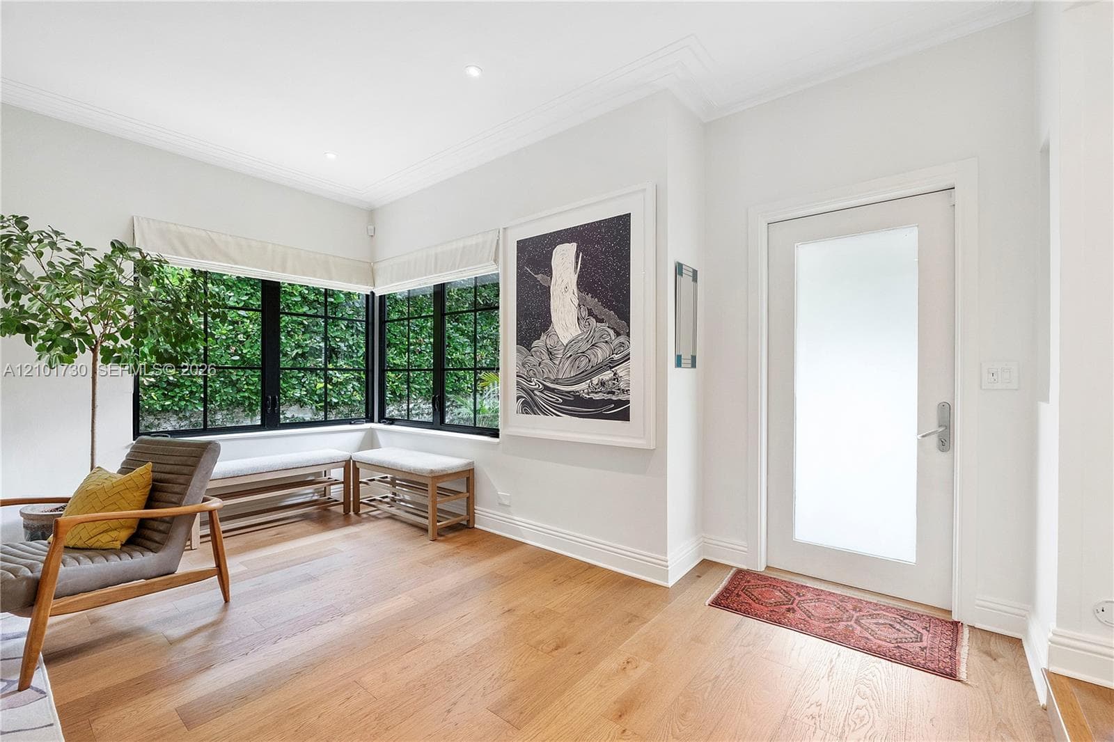 Entryway featuring wide-plank wood-finish flooring, recessed lighting, crown molding, a frosted-glass pane entry door, and floor-to-ceiling corner windows with black mullions