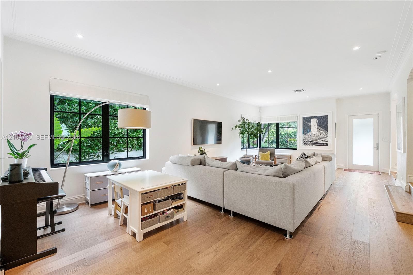 Open-concept room featuring wide-plank wood-finish flooring, recessed lighting, and large windows with black frames