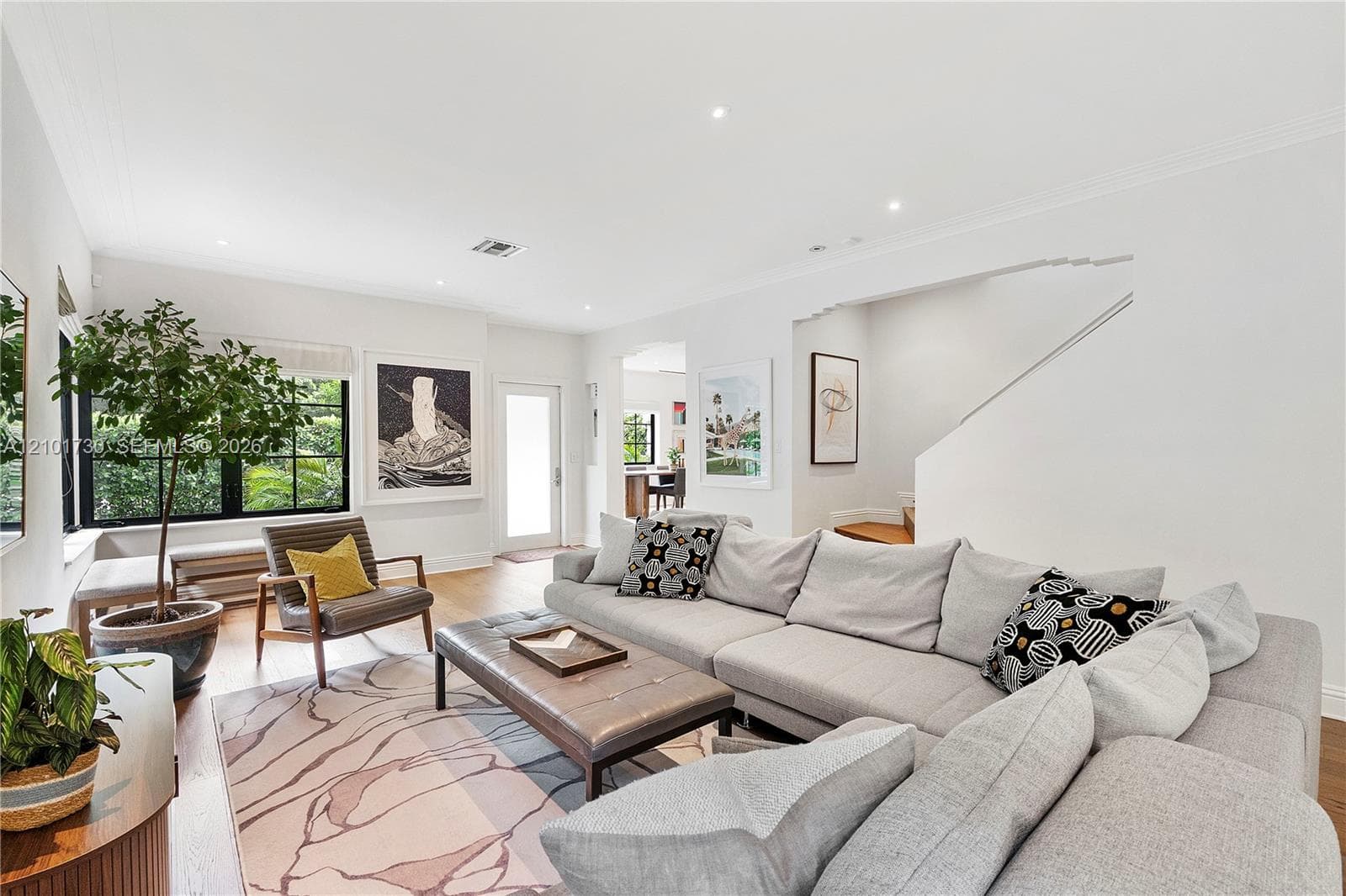 Living area featuring wood-finish flooring, recessed lighting, crown molding, and black-trimmed multi-pane windows