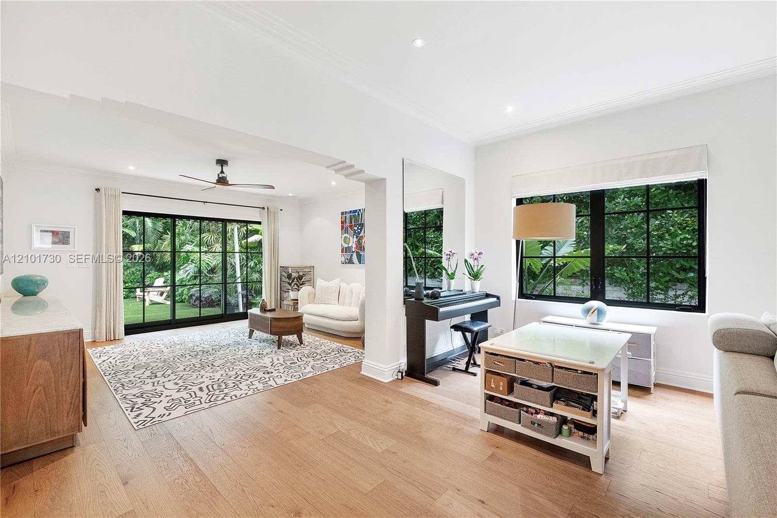 Open-concept interior featuring light wood-finish flooring, recessed lighting, and large windows with black mullions