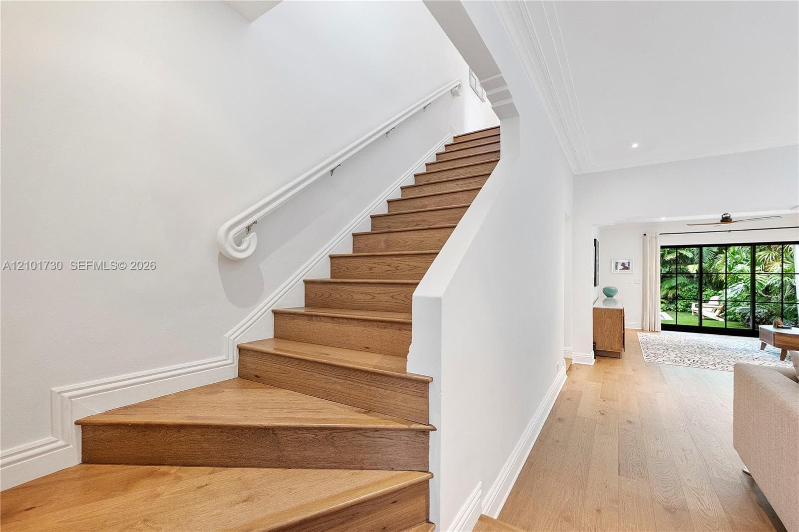 Staircase featuring wood-finish treads, a white handrail, and white millwork
