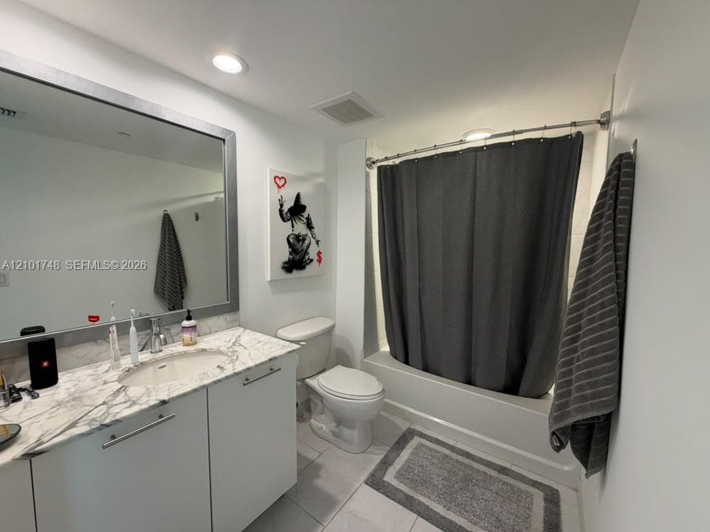 Vanity with a stone-finish countertop, undermount sink, and chrome faucet