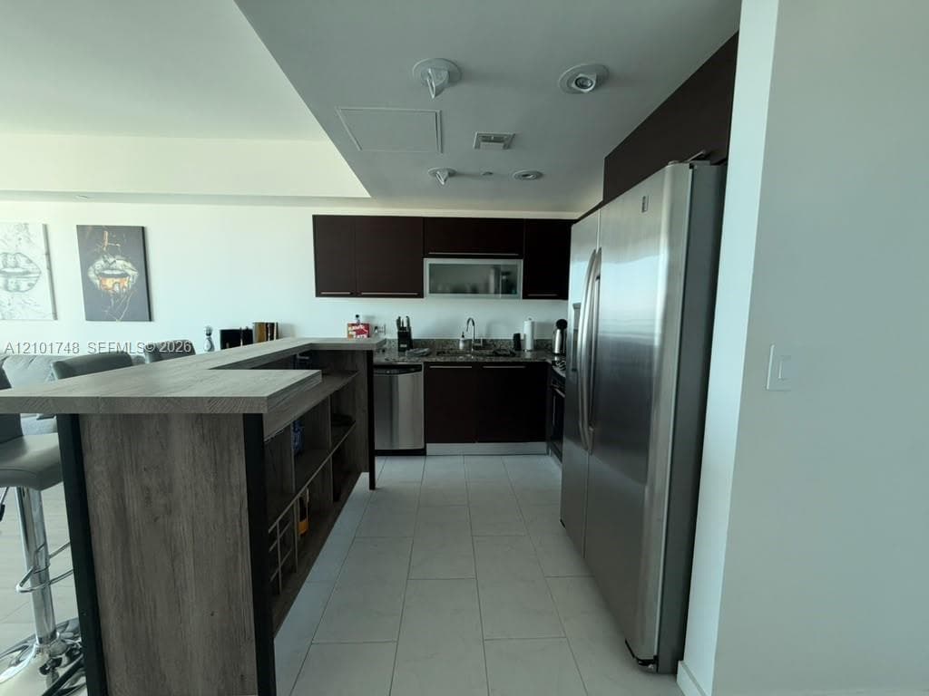 Kitchen featuring dark wood-finish cabinetry, stainless steel appliances, and a granite-finish countertop