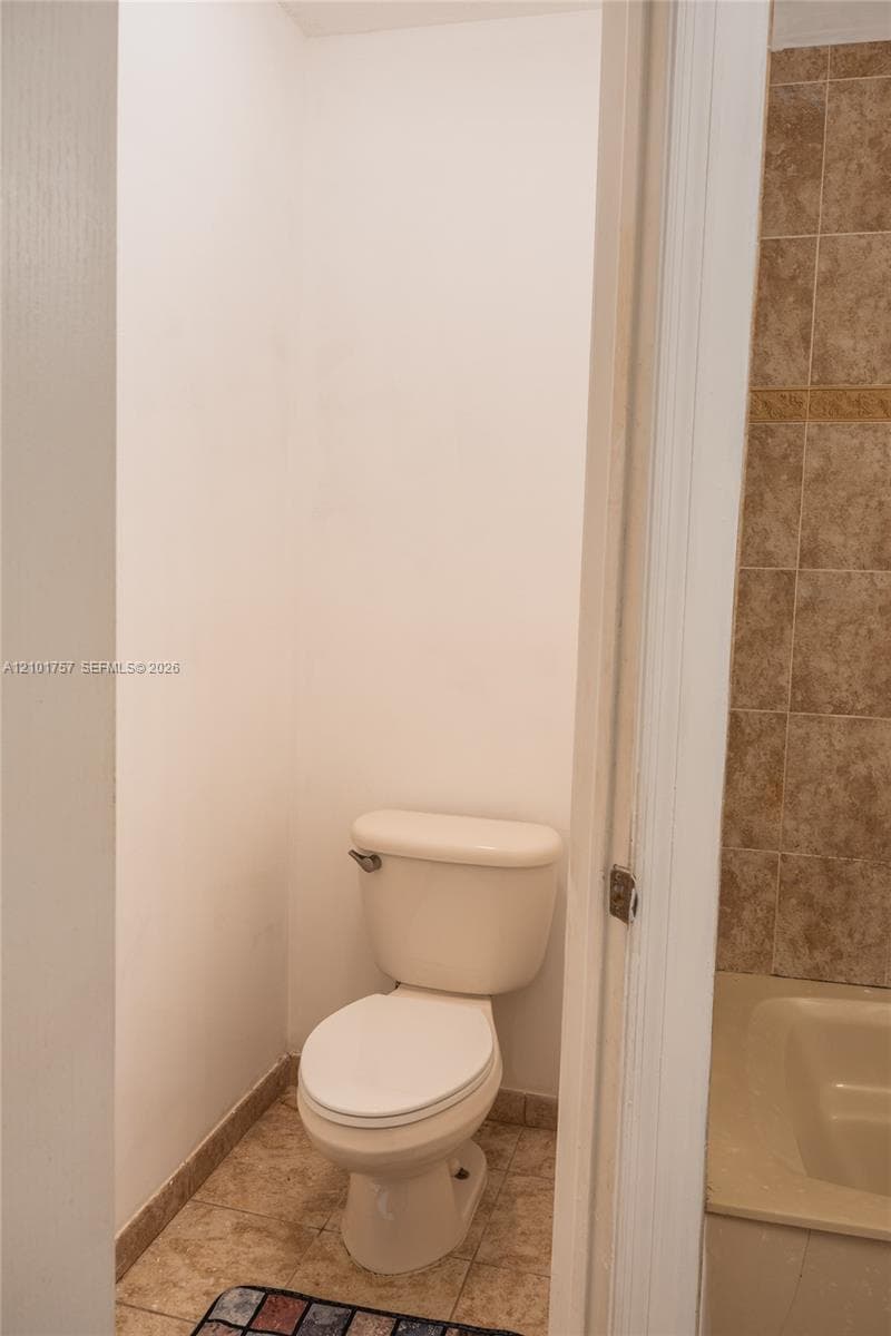 White toilet with tile flooring