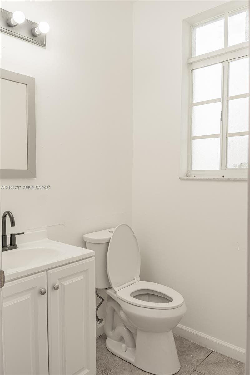 White vanity with a single basin, dark-finish faucet, and coordinating cabinet hardware