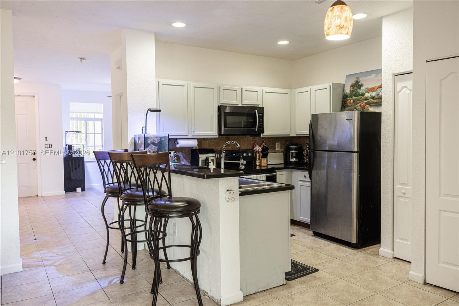Kitchen featuring white cabinetry, black countertops, stainless steel appliances, and recessed lighting