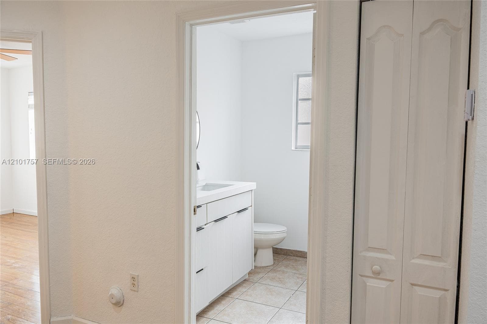 Bathroom with a white vanity and integrated sink, round mirror, and tile flooring