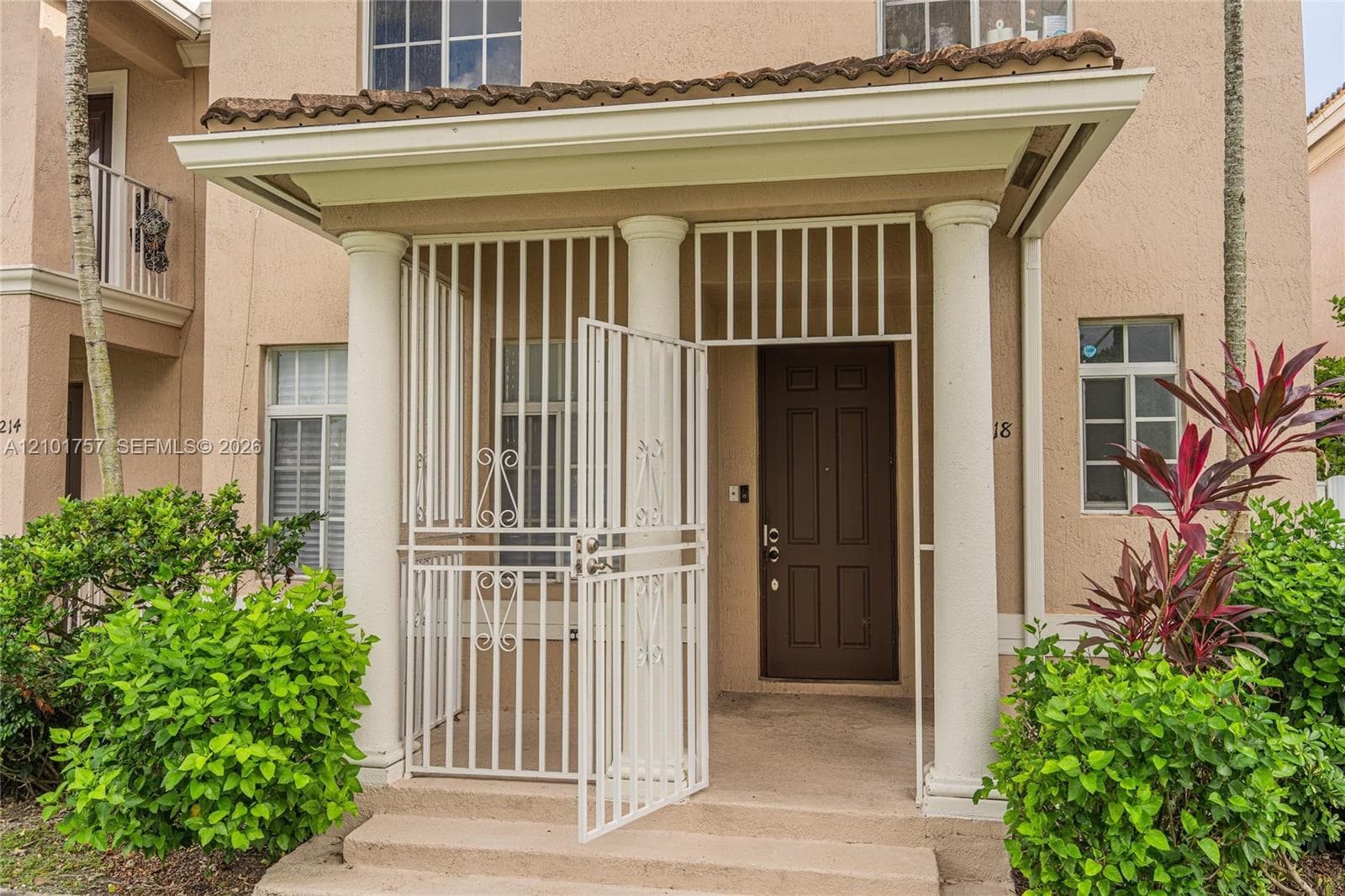 Covered entry with prominent columns, a paneled entry door, and decorative ironwork