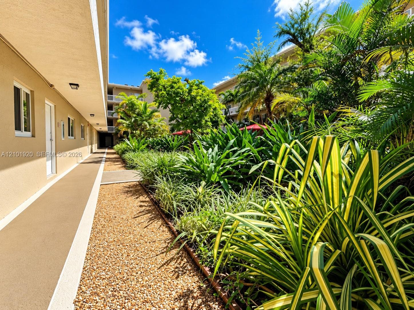 Multi-story stucco exterior featuring arched balconies, white railings, and dedicated off-street parking