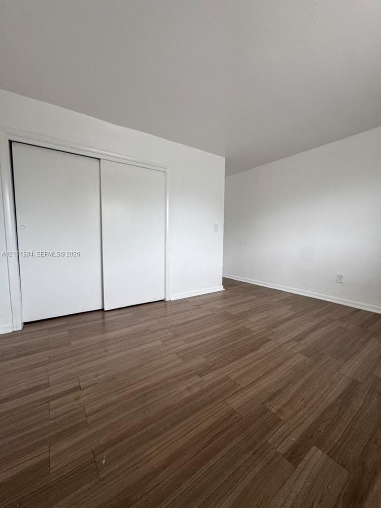 Wood-finish flooring and white walls complemented by a sliding-door closet