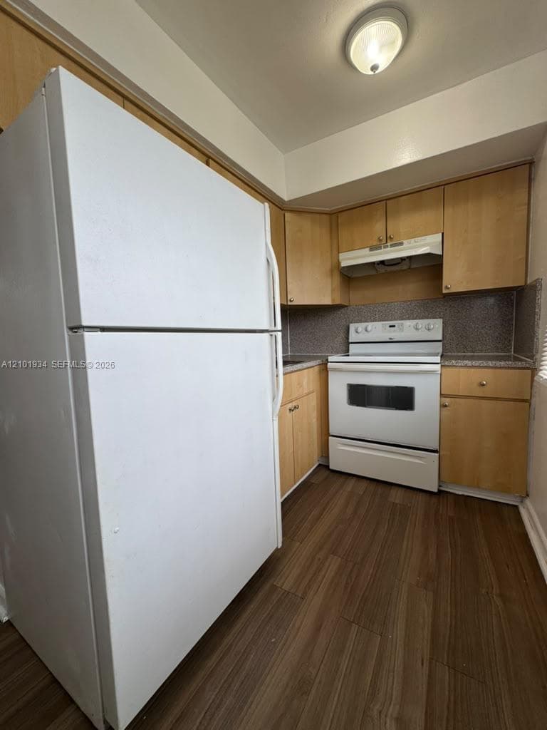 Kitchen featuring light-finish wood cabinetry, wood-finish flooring, stone-finish countertops, and white appliances including a range and refrigerator