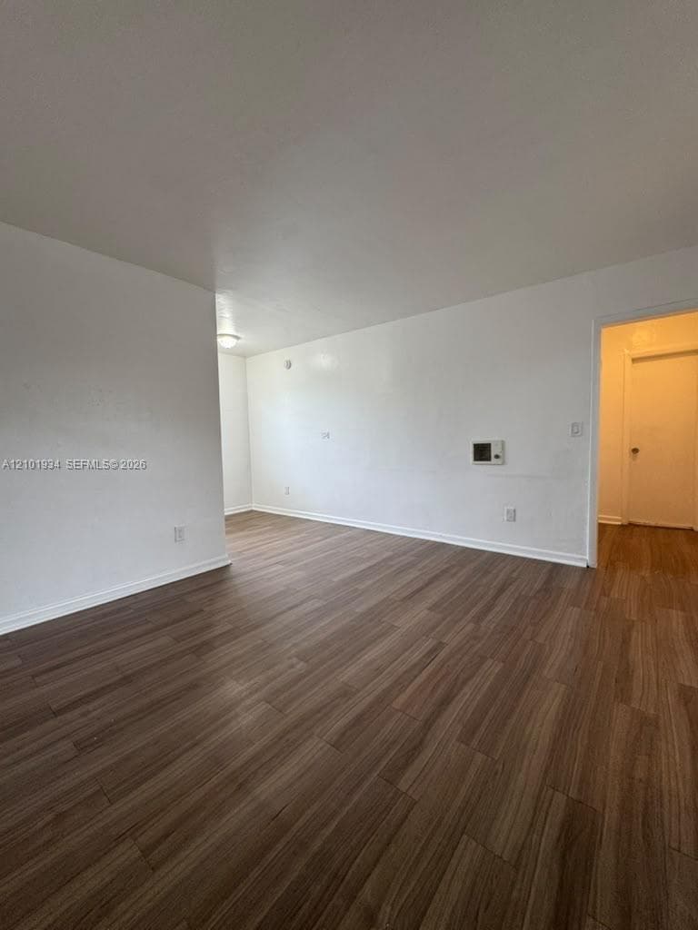 Interior space featuring wood-finish flooring, smooth wall surfaces, and a wall-mounted heater unit
