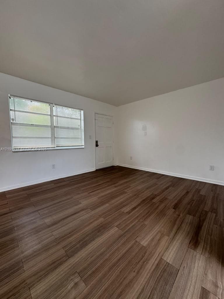 Interior room featuring wood-finish flooring, a multi-pane horizontal sliding window, and a paneled entry door