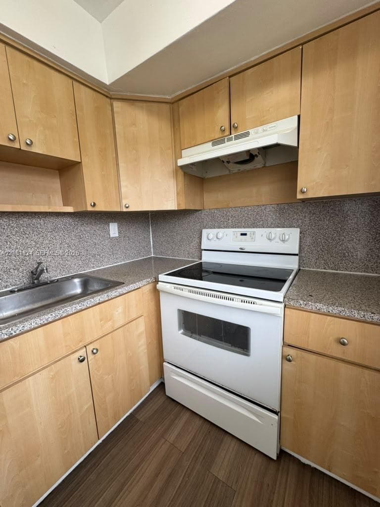 Kitchen featuring light-finish cabinetry, speckled countertops, an integrated range hood, a stainless steel sink with a faucet, and wood-finish flooring
