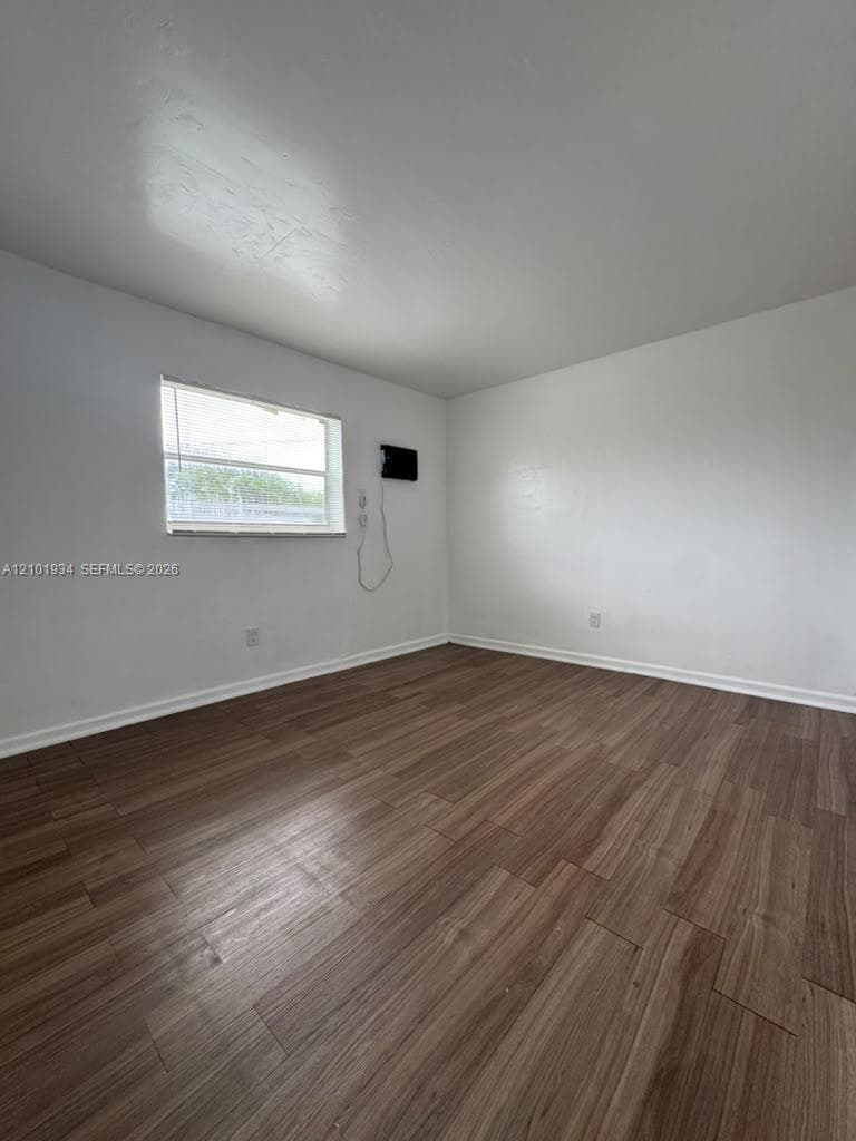 Neutral interior space featuring wood-finish flooring, smooth white walls, and a single-pane horizontal window
