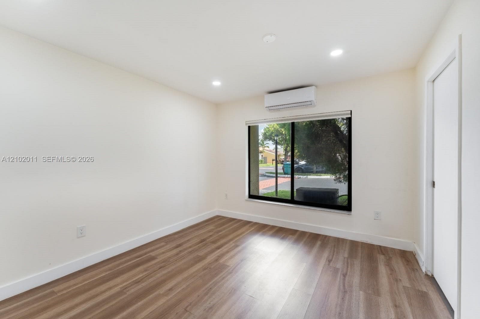Wood-finish flooring, recessed lighting, and a split-system air conditioning unit