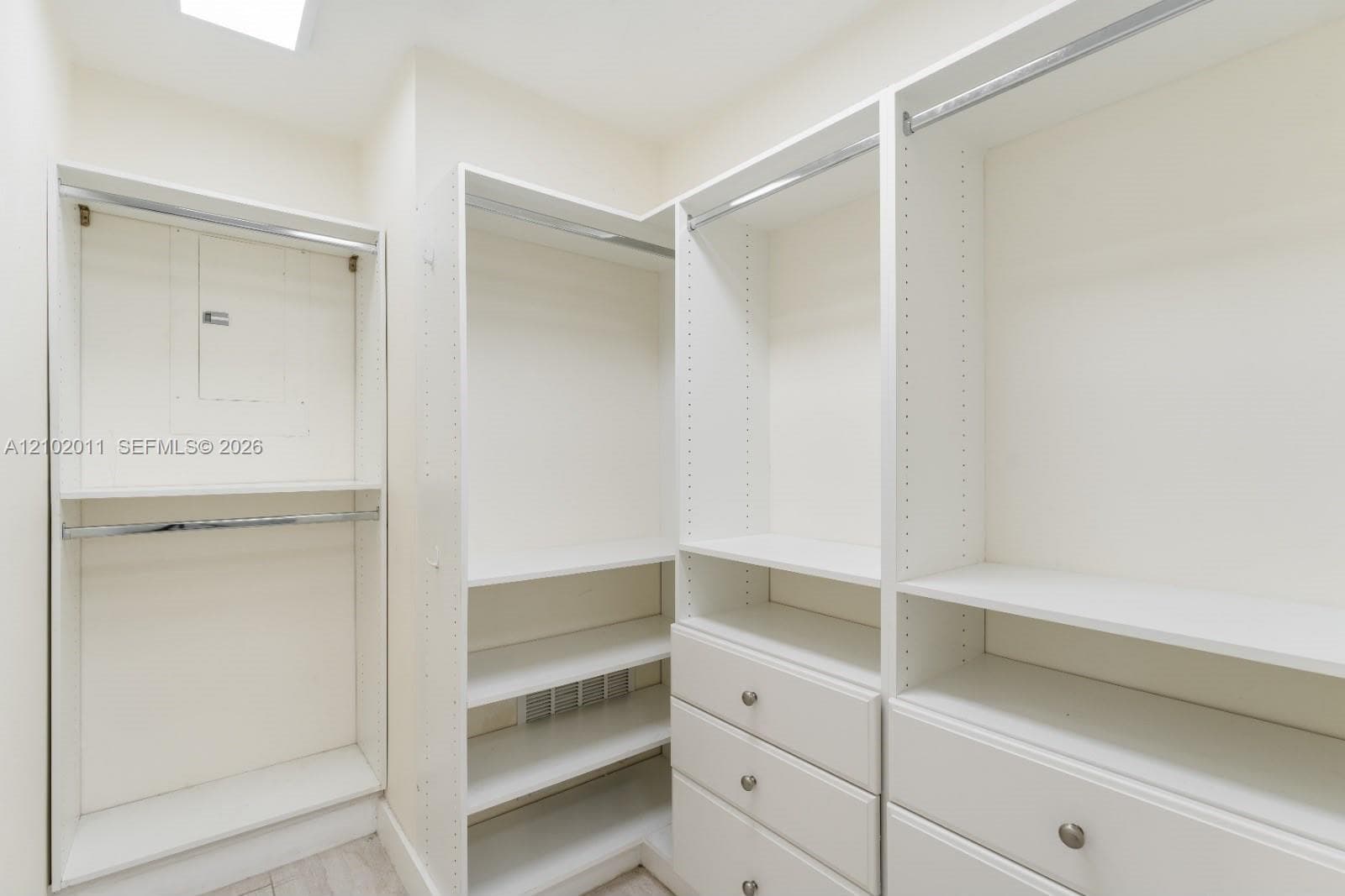 Custom closet system with multiple hanging rods, integrated shelving, and built-in drawers