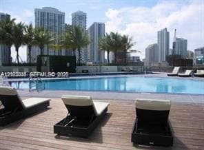 Swimming pool with a tile perimeter, complemented by a wood-plank deck and palm tree landscaping