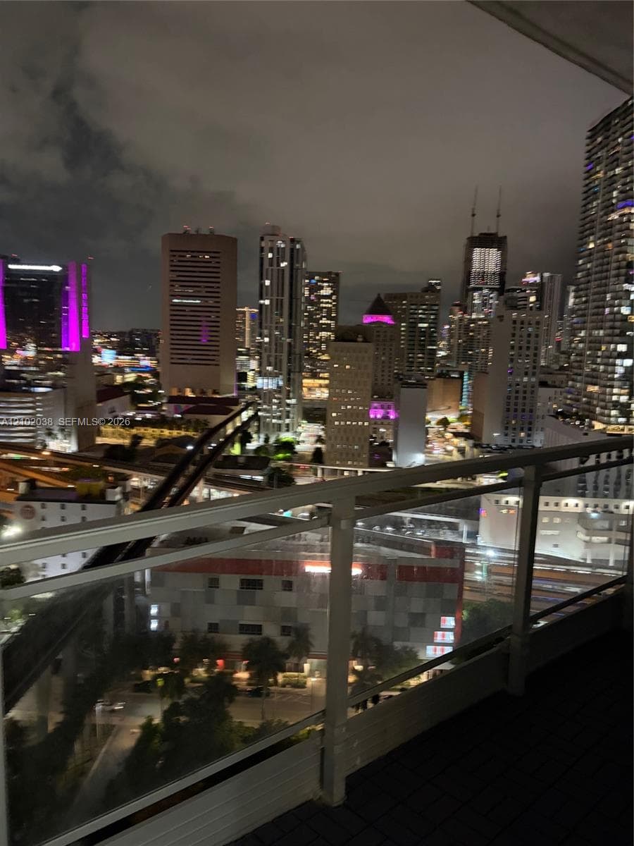 Private outdoor balcony featuring a glass panel railing and urban skyline backdrop