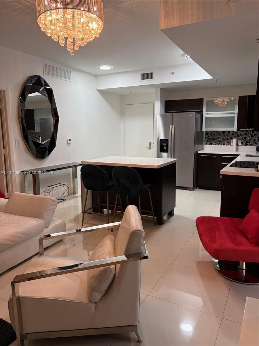 Open-concept kitchen featuring dark cabinetry, quartz , a central island, stainless steel refrigerator, and recessed lighting