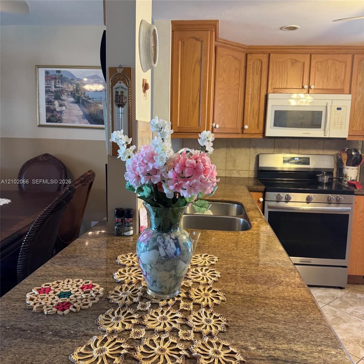 Kitchen featuring stone-finish countertops, stainless steel appliances, dual-basin sink, and natural wood cabinetry