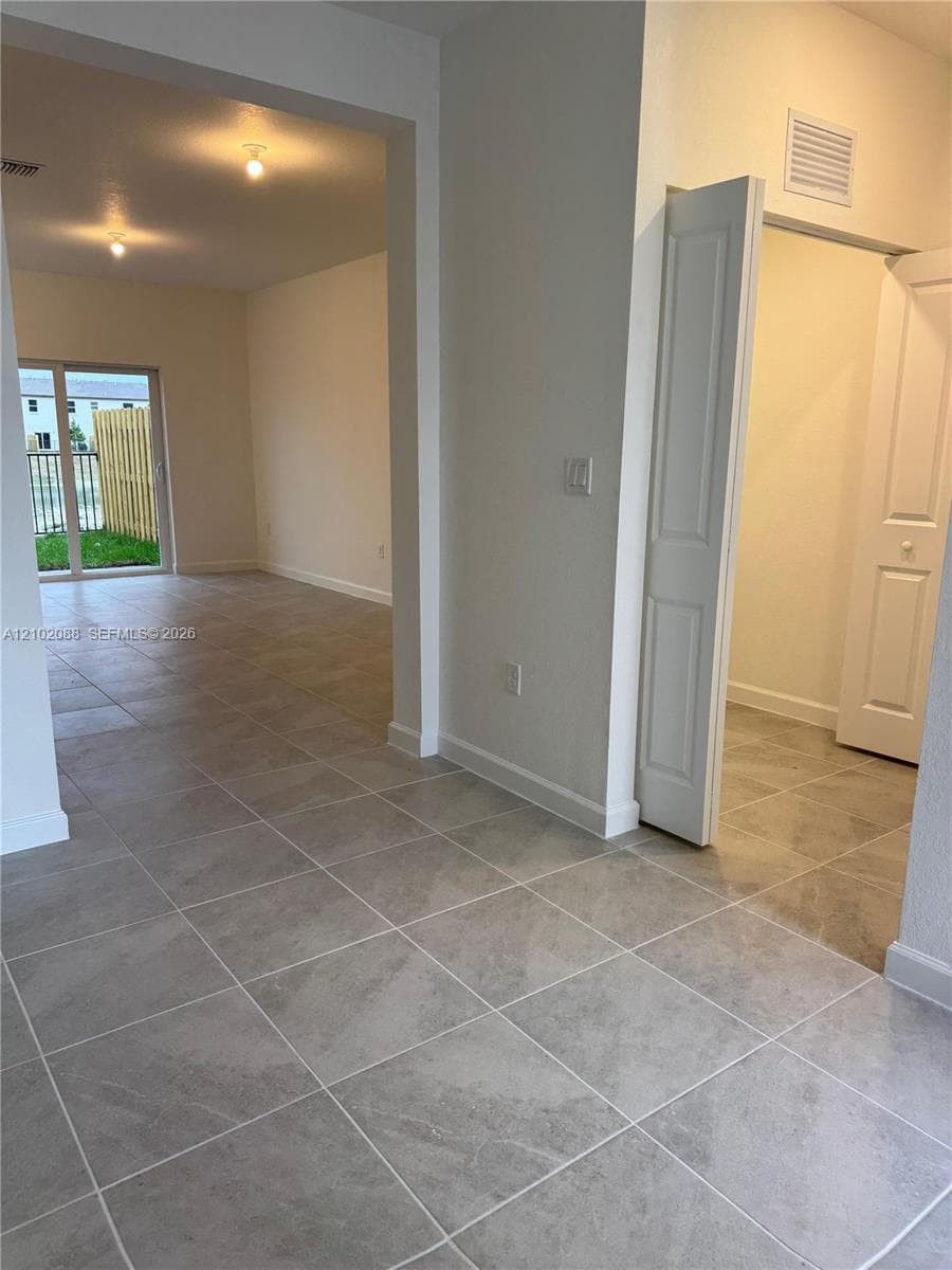 Large-format tile flooring, sliding glass door, and interior closet with dual-panel doors