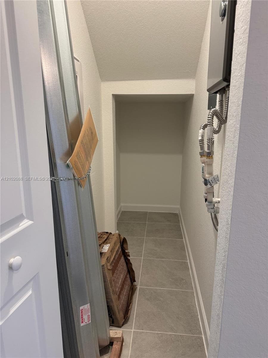 Recessed storage area featuring neutral-toned floor tile and painted walls