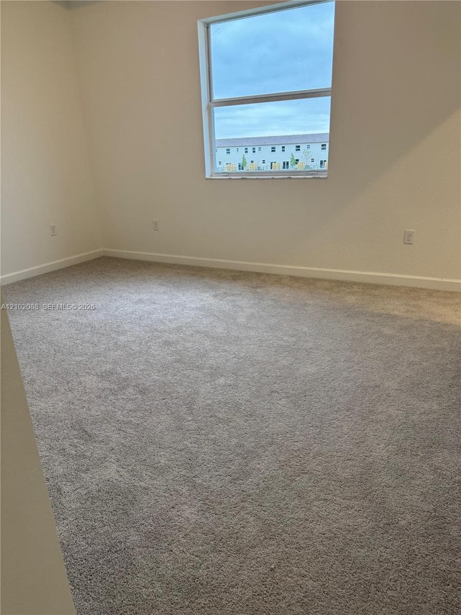 Neutral-toned carpeting, high-gloss white walls, and a single-pane window with natural light