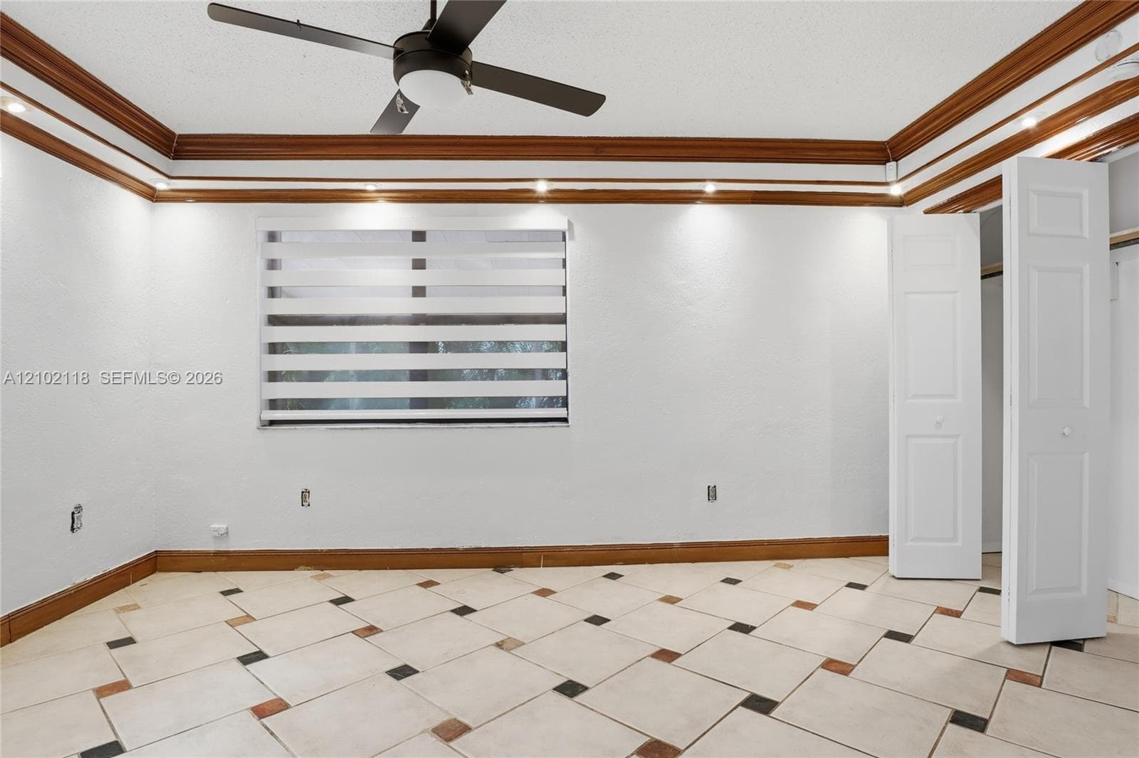 Room featuring ceramic tile flooring with geometric inlays, crown molding with recessed lighting, and a ceiling fan