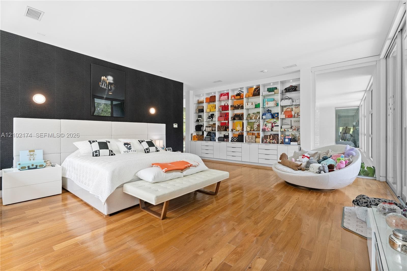 Double-height living area with floor-to-ceiling glass walls, polished concrete flooring, open-concept kitchen with built-in cabinetry, and wood-finish bridge balcony