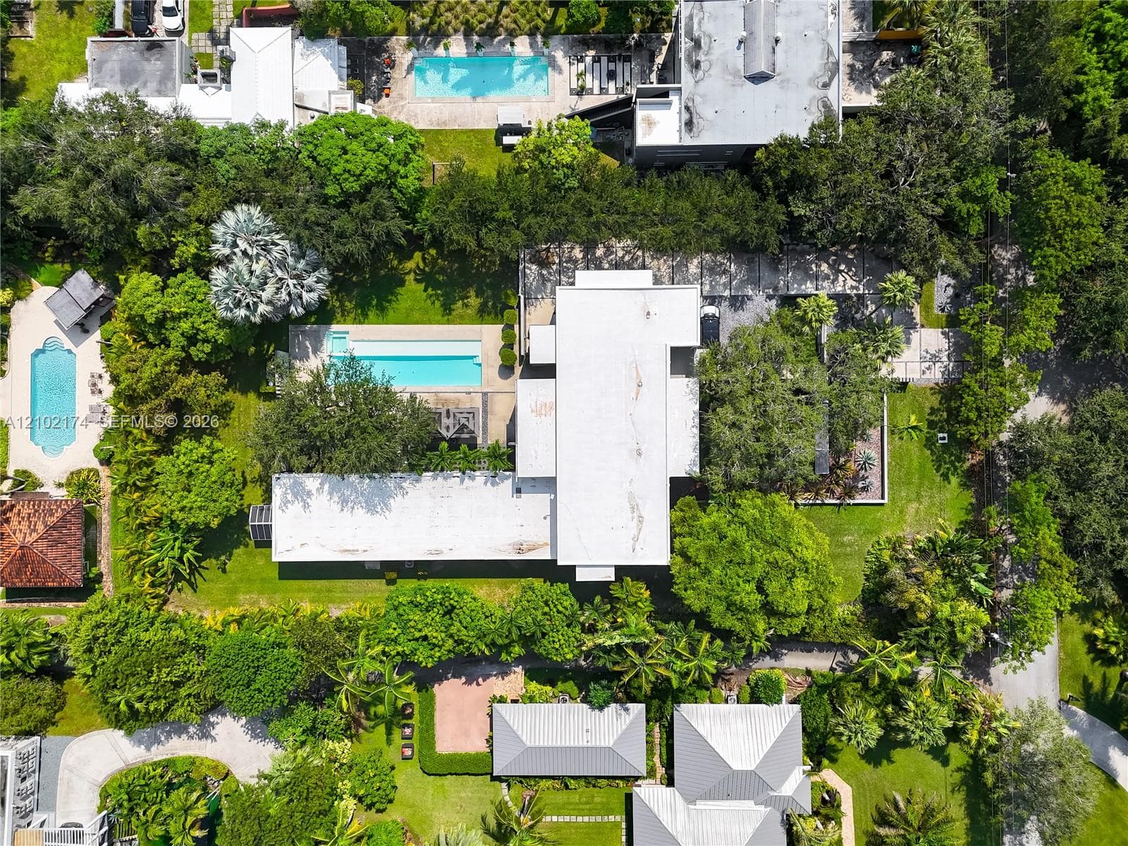 Aerial perspective featuring a residential lot with a rectangular swimming pool, expansive grounds, and mature tree canopy