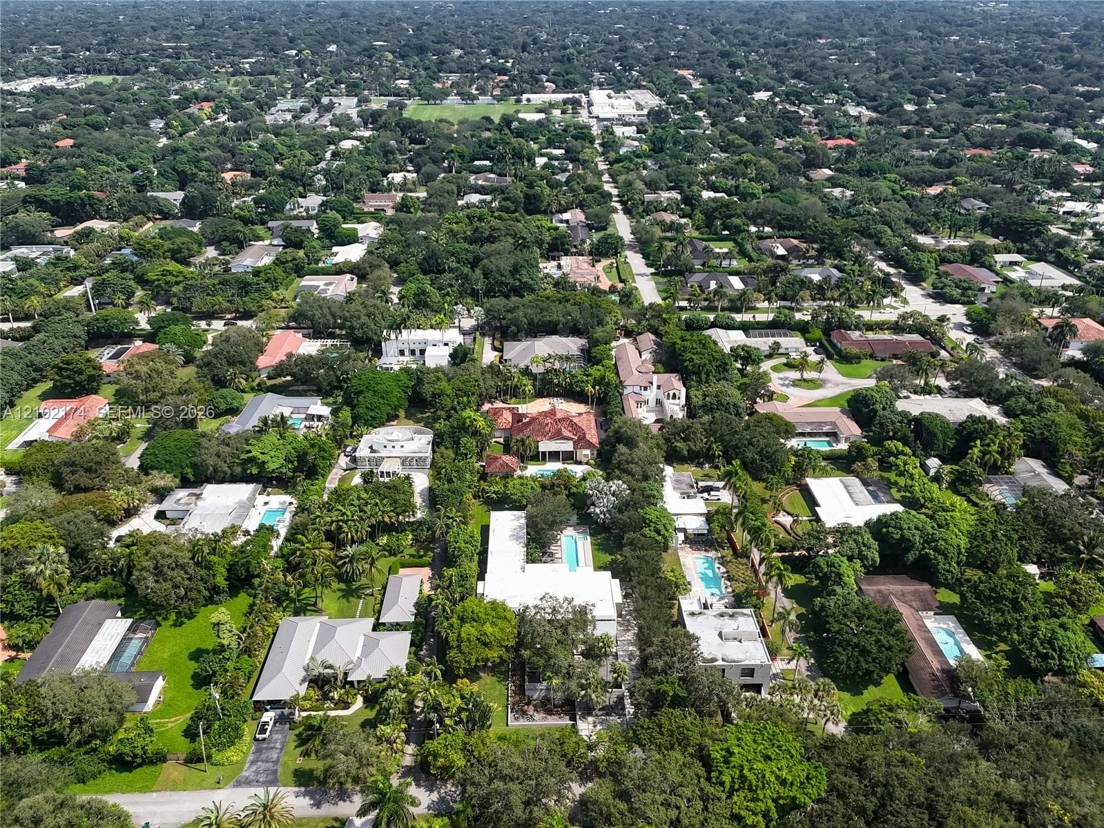 Aerial view of the property featuring a rectangular swimming pool, expansive green space, mature landscaping, and a multi-section roofline