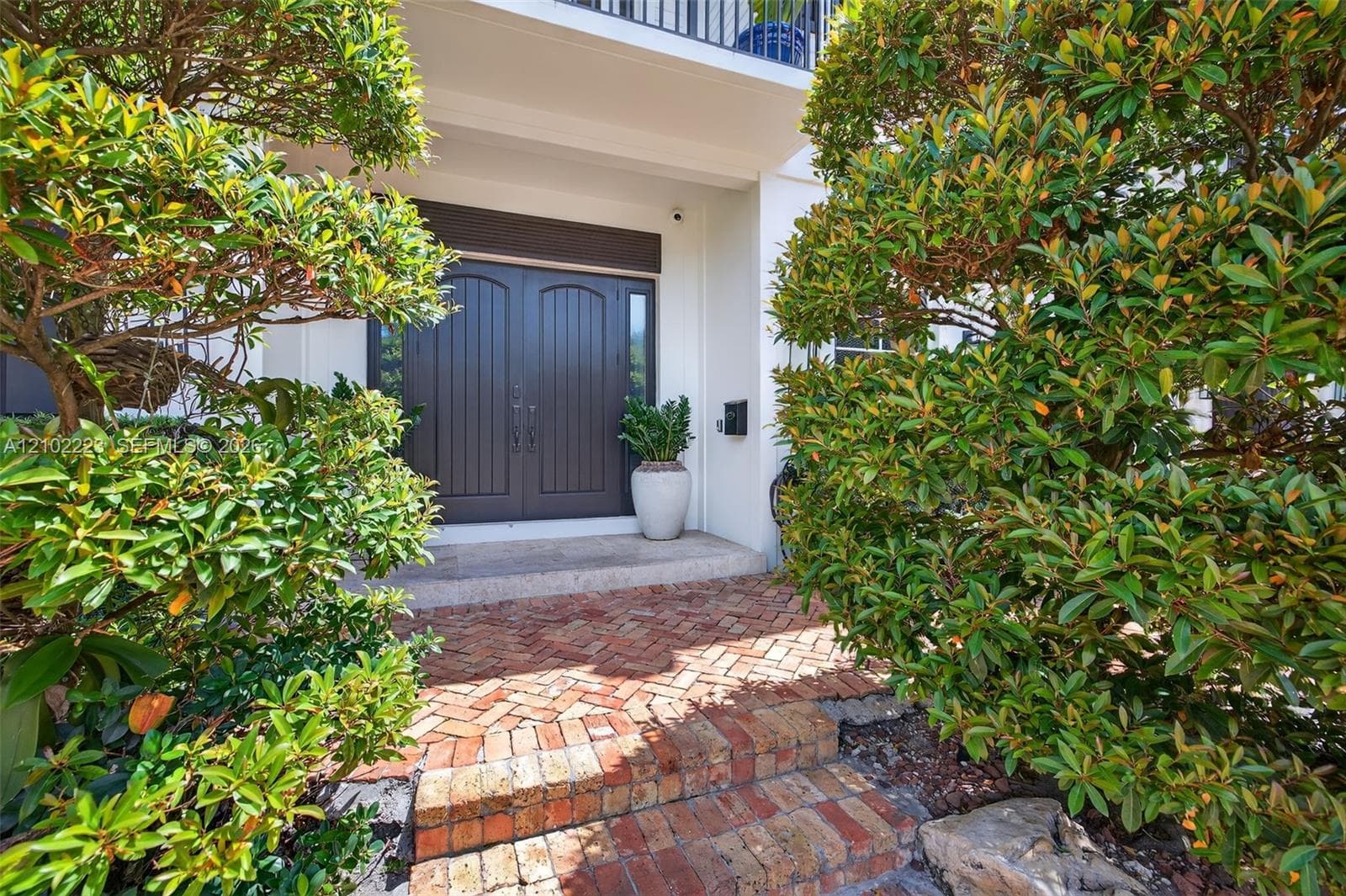 A distinguished entrance framed by lush Tropical Landscaping with beautiful brick paver steps lead to an elegant, natural stone, Landing and impressive double entry doors a striking first impression that Heit at the grandeur and exceptional proportions awaiting inside this remarkable Rio Vista residence.
