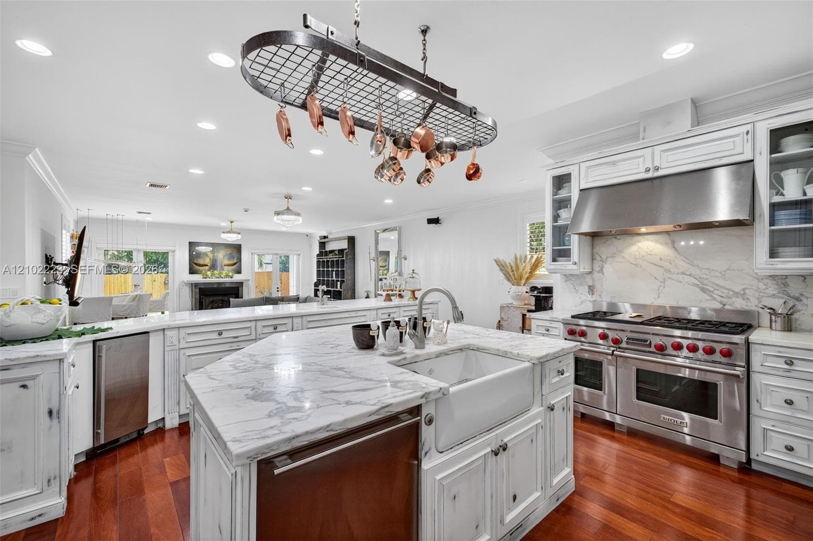 A chef’s kitchen with personality and character featuring distinctive, distressed, finish cabinetry, Premium, Wolf, Appliances, and beautiful marble stone countertops a unique blend of rustic charm and modern culinary luxury creates a space that’s as inviting as it is functional.