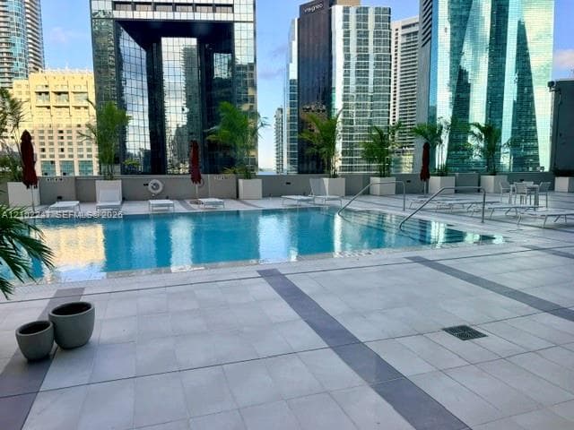 8th floor swimming pool featuring a large concrete sun deck, integrated steps with handrails, and surrounding skyscraper backdrop
