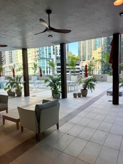 Covered pool terrace featuring large-format tile flooring, structural wooden pillars, and a ceiling-mounted fan