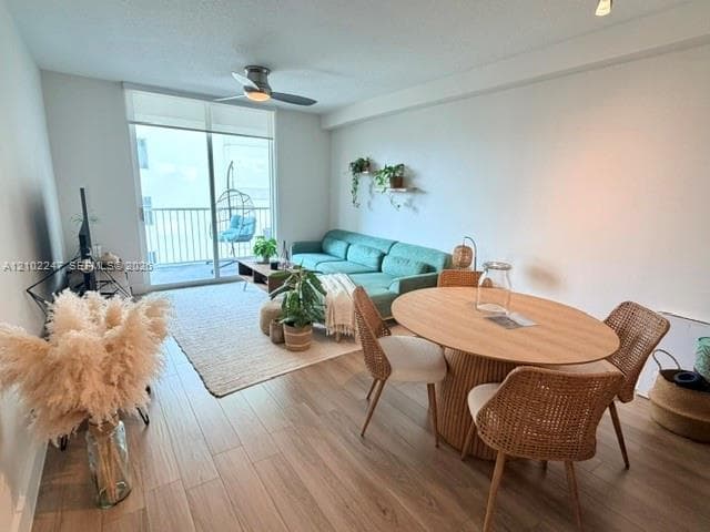 Open-concept room featuring wood-finish flooring, a ceiling fan, and sliding glass doors leading to a balcony