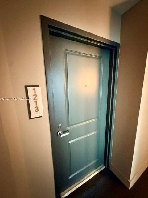 Two-panel entry door finished in a deep navy tone, featuring a satin-finish lever handle, integrated peephole, and a minimalist wall-mounted unit identifier