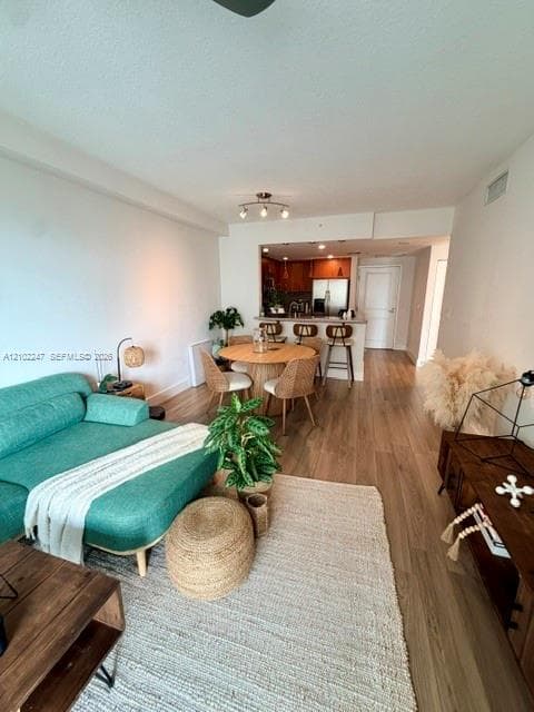 Wood-finish flooring, breakfast bar, and track lighting