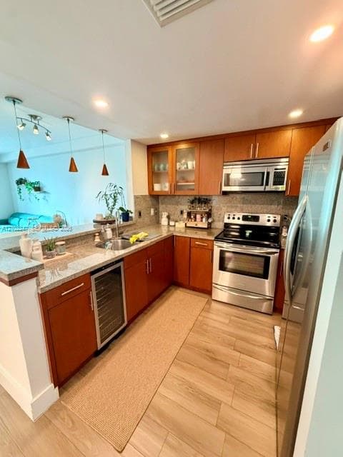 Kitchen featuring wood cabinetry, stone countertops, stainless steel appliances, built-in wine refrigerator, and wood-finish flooring