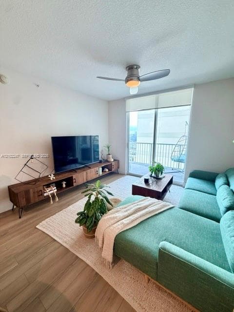 Wood-finish flooring, central ceiling fan with integrated light, and large glass sliding doors providing exterior access