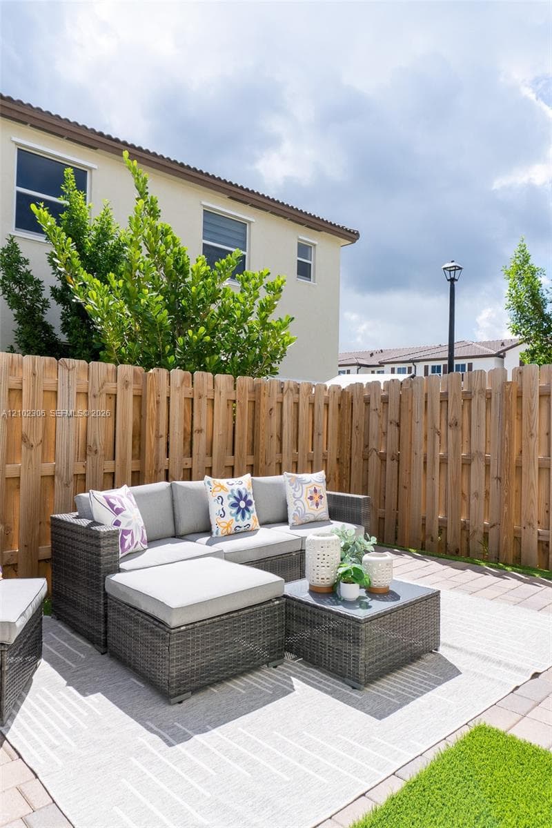 Enclosed backyard featuring vertical wood fencing, paver patio, and low-maintenance turf area