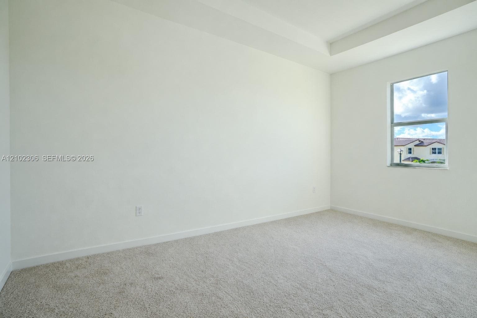 Neutral-toned interior room featuring wall-to-wall carpeting, a recessed ceiling detail, and a single-pane window