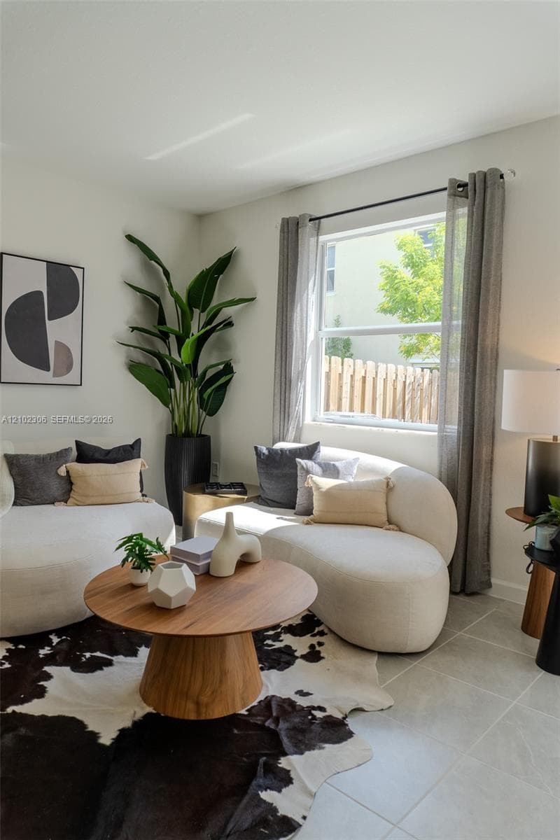 Neutral-toned interior featuring large-format tile flooring, crisp painted walls, and a substantial window with installed curtain rod hardware