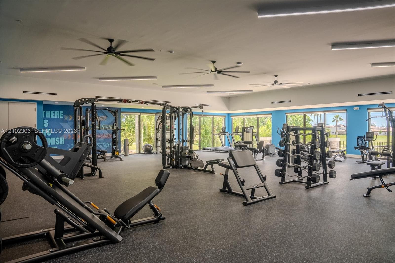 Fitness center featuring rubber flooring, ceiling-mounted fans, linear lighting fixtures, and floor-to-ceiling windows