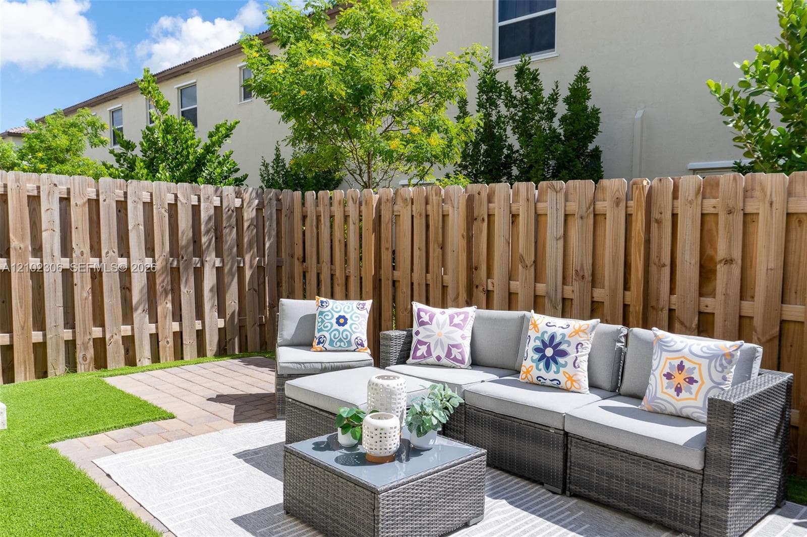 Fenced backyard featuring a wood privacy fence, paved patio area, and synthetic turf lawn