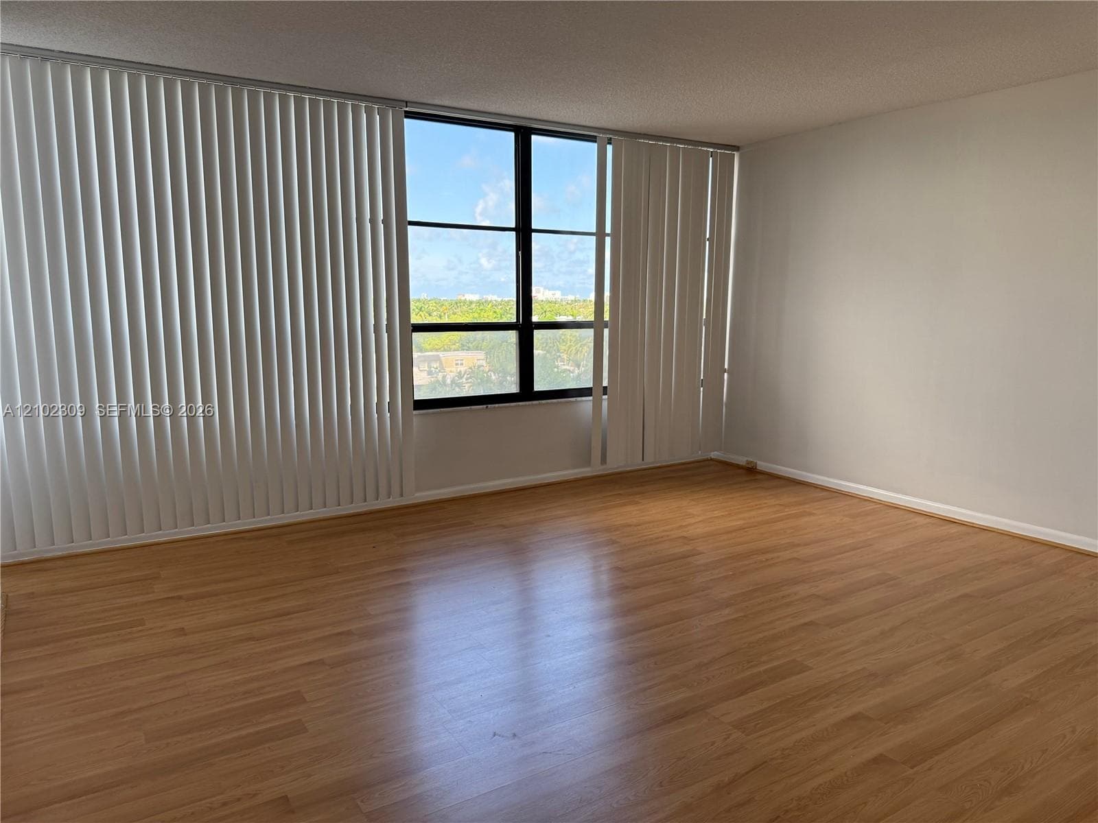 Open living area featuring wood-finish flooring, floor-to-ceiling windows, and vertical blinds