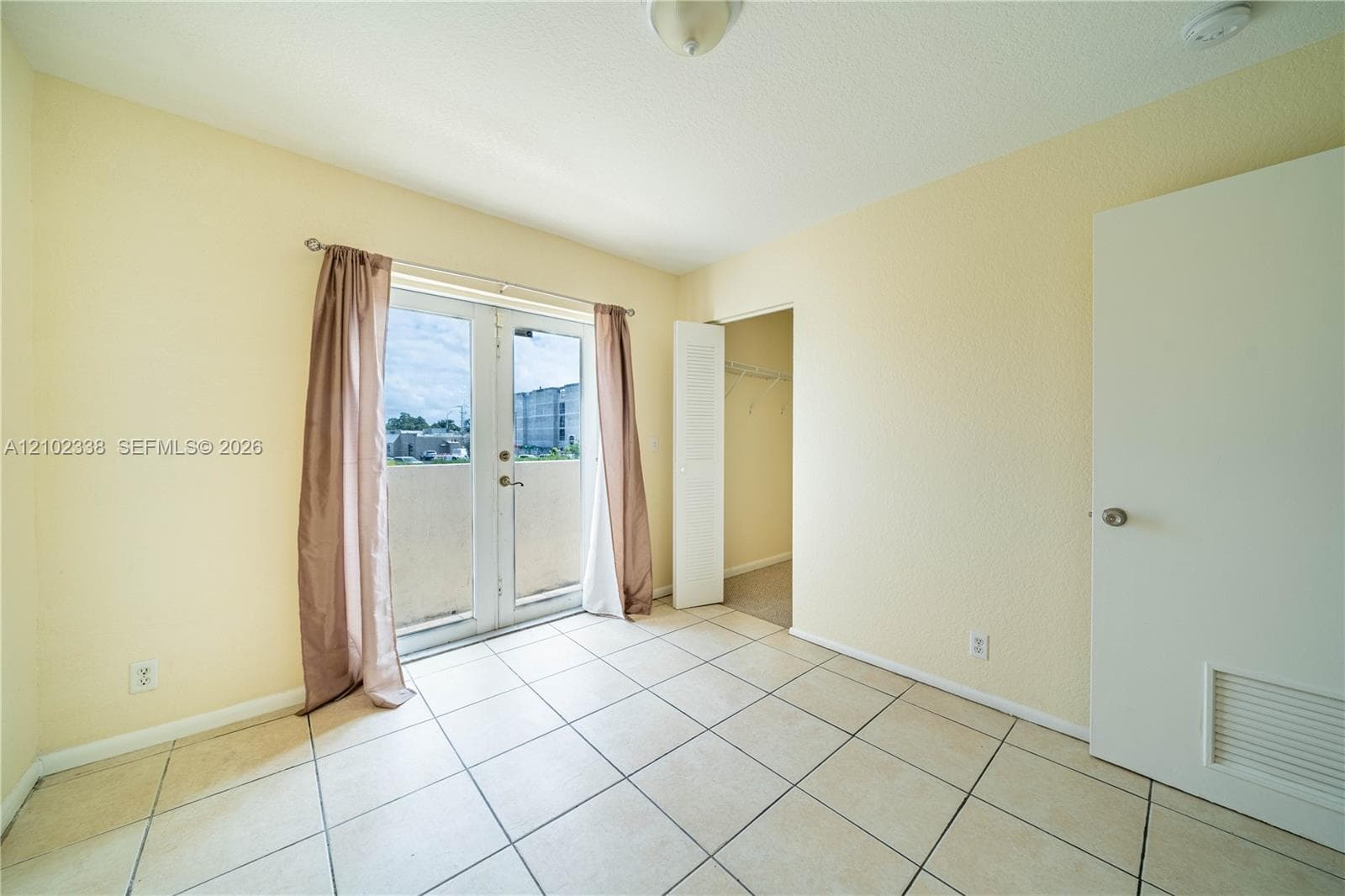 Tile flooring extending throughout, complemented by a pair of French doors