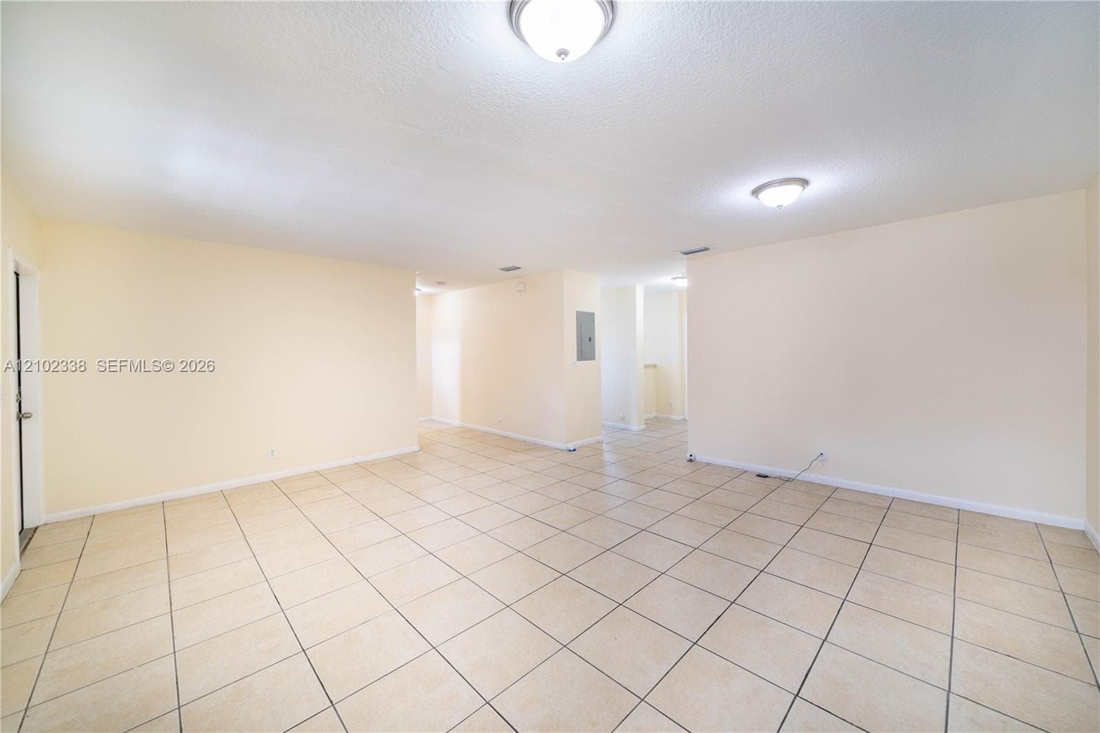 Spacious room with light-colored tile flooring and recessed ceiling lighting